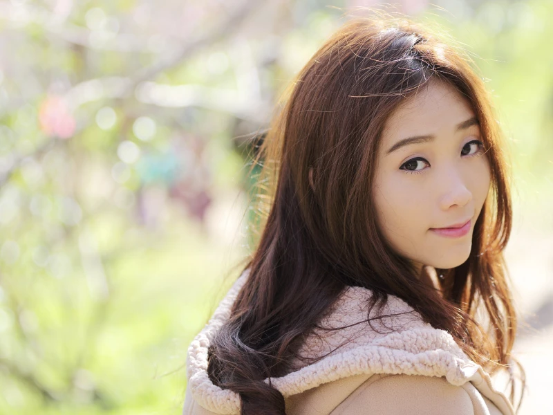 明るめのブラウン系の髪色をして微笑みながら振り買っている女性