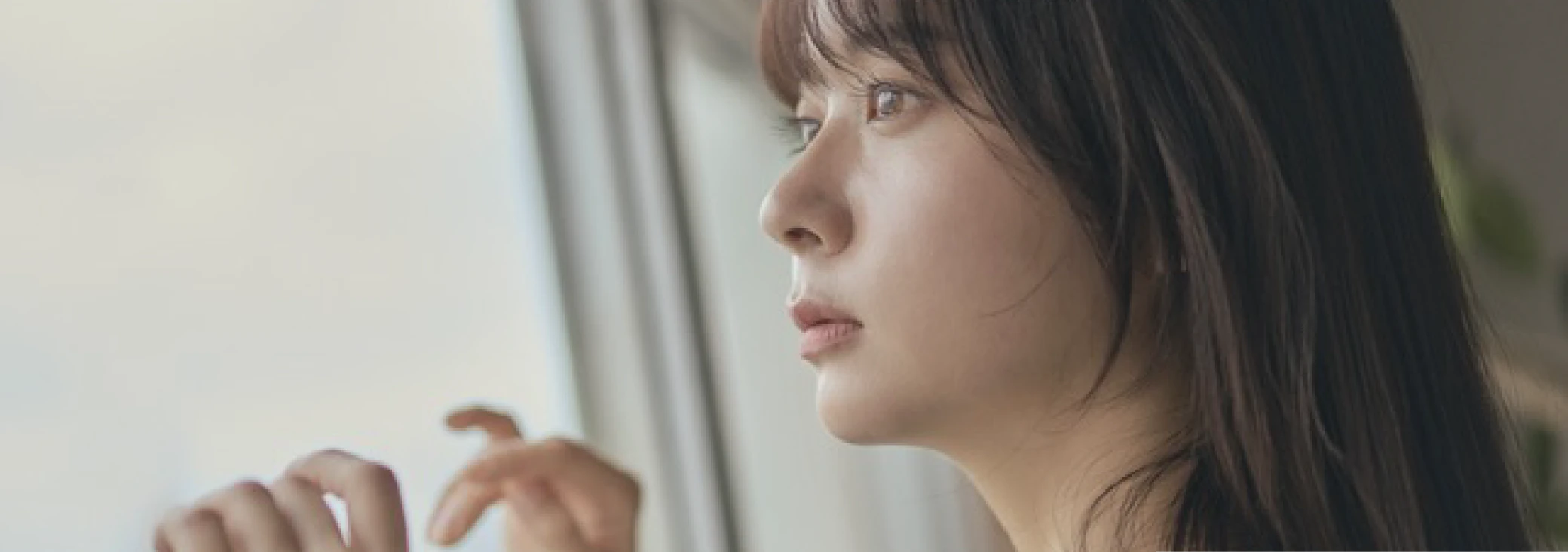 グレージュの髪色をして窓の外を眺めている女性