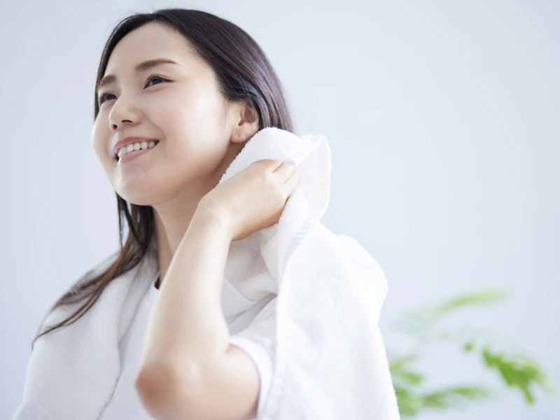 髪をタオルで拭きながら微笑んでいる女性