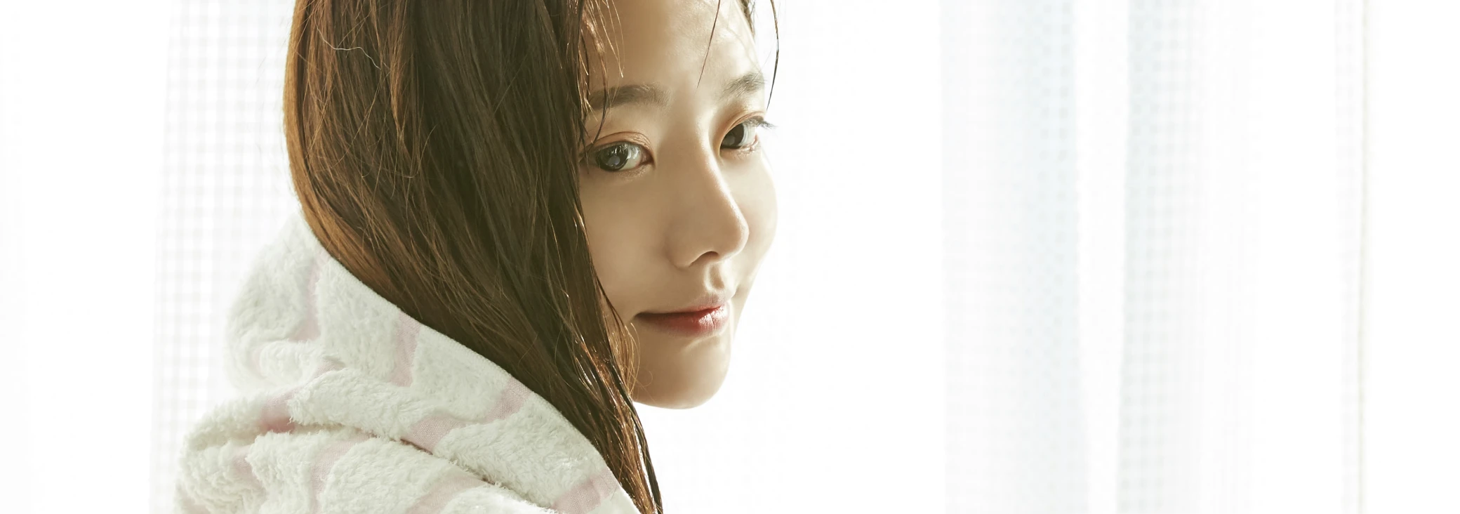 洗髪後の濡れた髪をタオルで拭いている女性