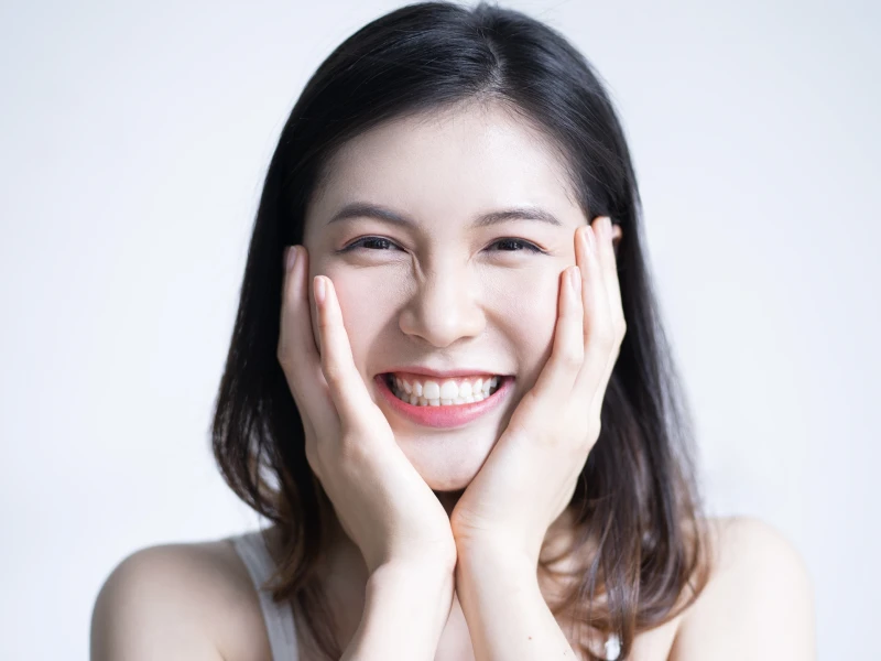 両頬に手を当てて嬉しそうに笑っている女性