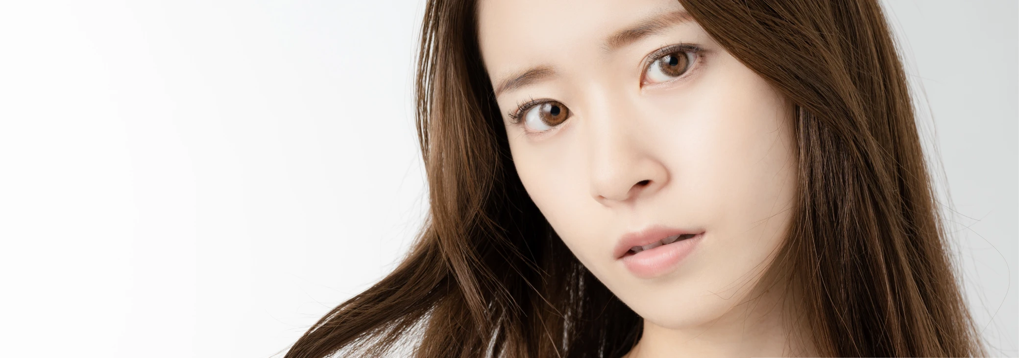 毛先をつまみながら不安そうな表情をしている女性