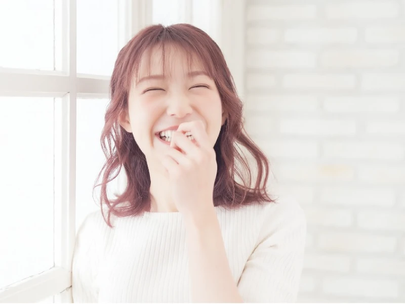 暗めのピンクの髪色をして笑っている女性