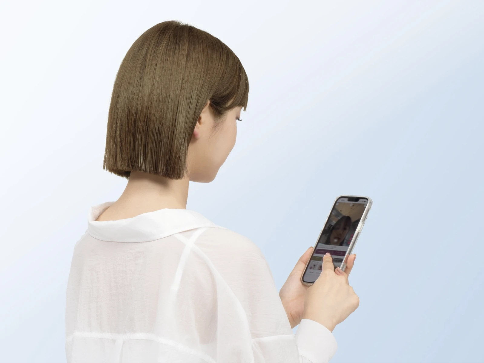 ビューティラボ/シフォンベージュの髪色をしてスマホで髪色シミュレーションを活用して髪色診断をしている女性の後ろ姿