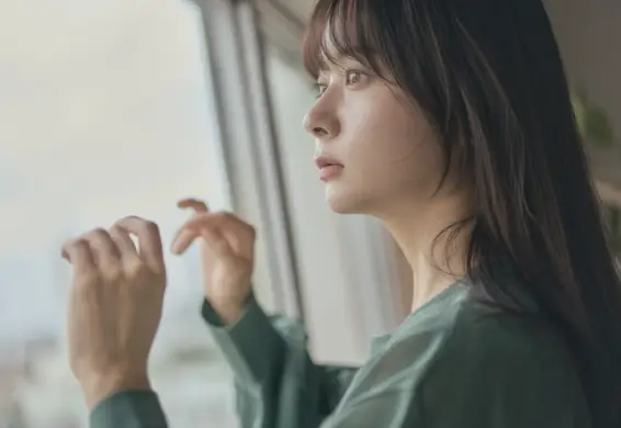 グレージュの髪色をして窓の外を眺めている女性