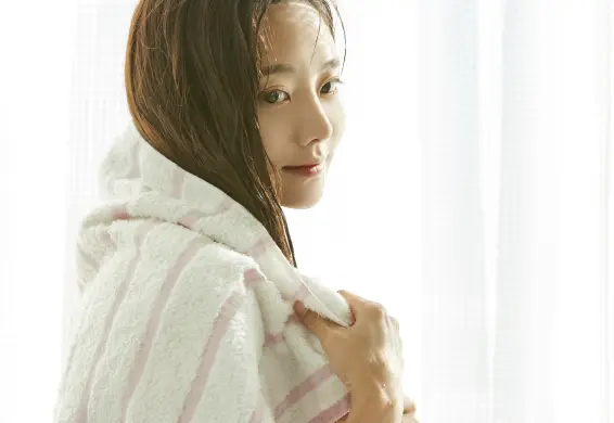 洗髪後の濡れた髪をタオルで拭いている女性