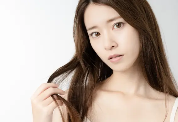 毛先をつまみながら不安そうな表情をしている女性