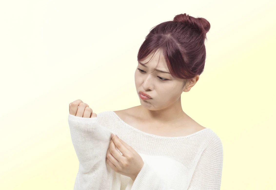 ビューティラボ/さくらピンクの髪色をして洋服の袖口についたカラー剤を困った表情で見つめている女性